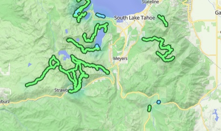 A light terrain map around South Lake Tahoe with numerous green activity routes and a blue lake
