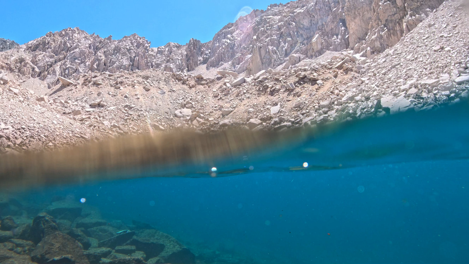 Crystal-clear alpine tarn with a split view above and below the waterline