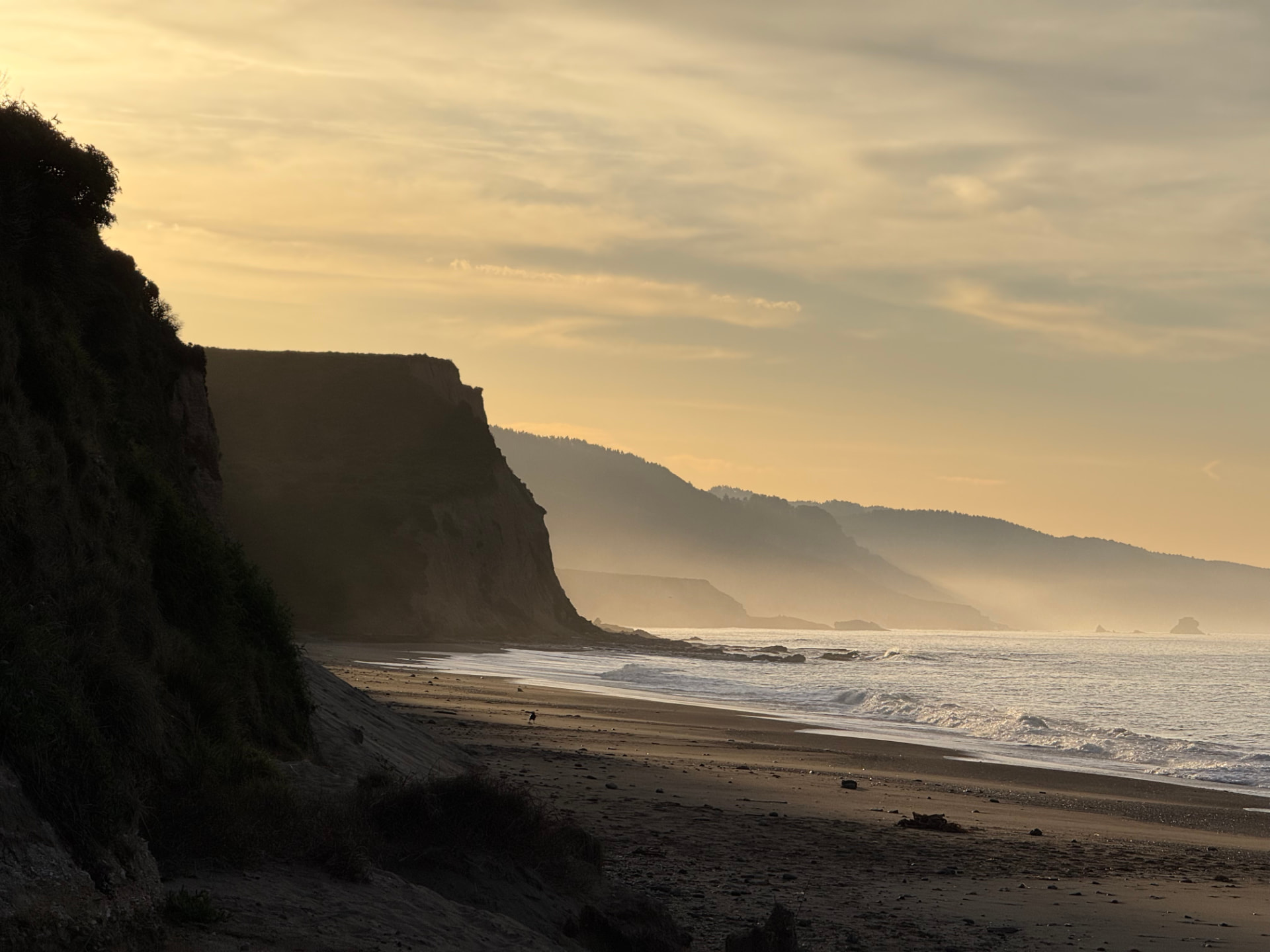 Misty coastal cliffs and a quiet beach at golden hour
